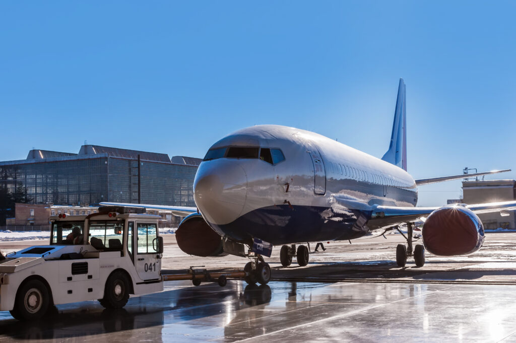 TUG Pushback tractor carries a passenger jet in hangar